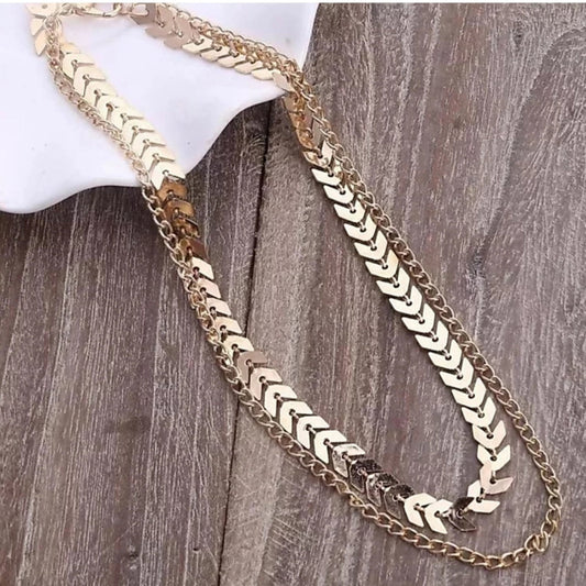 Gold chain necklace on a mannequin arm against a wooden background.