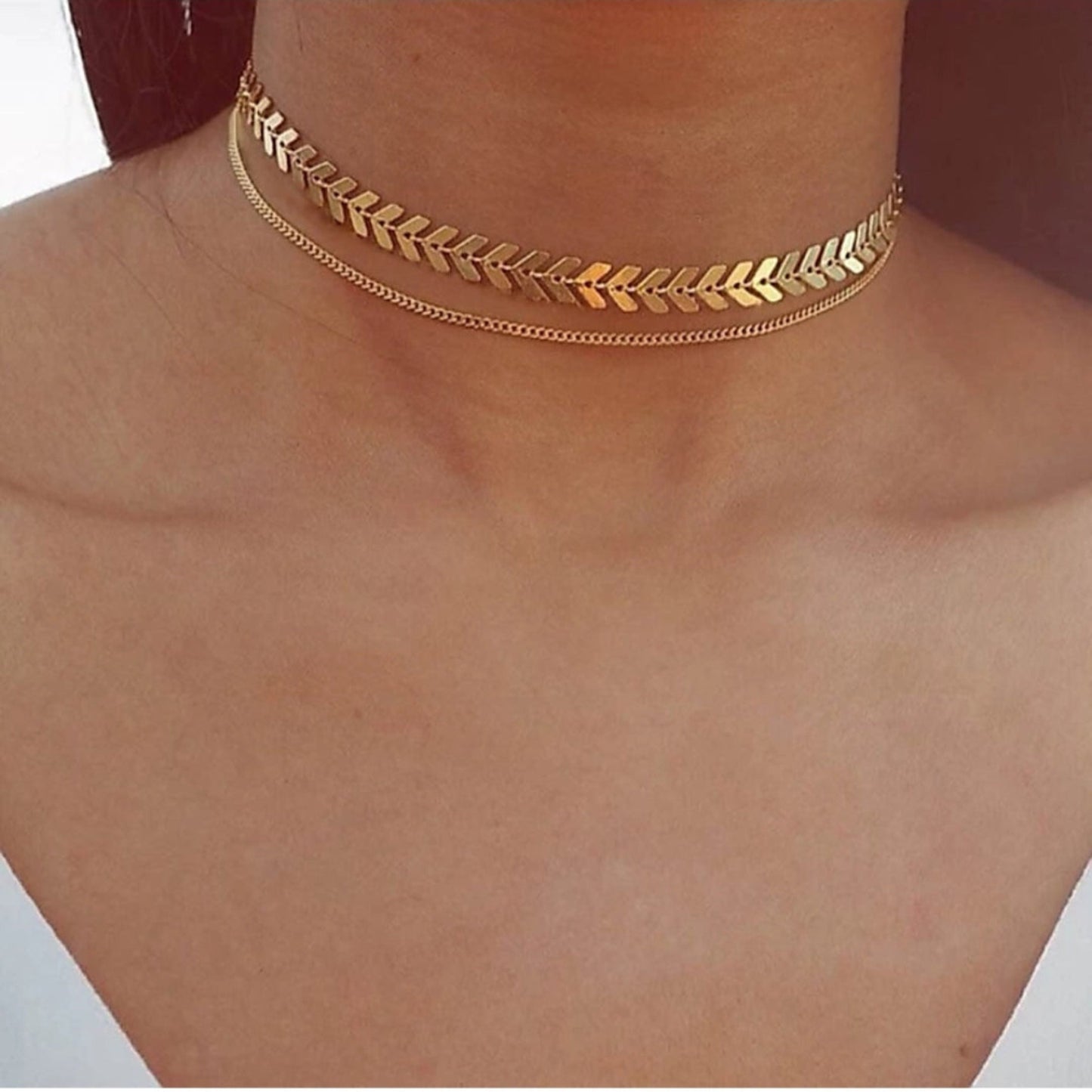 Gold leaf-patterned choker necklace on a person's neck.