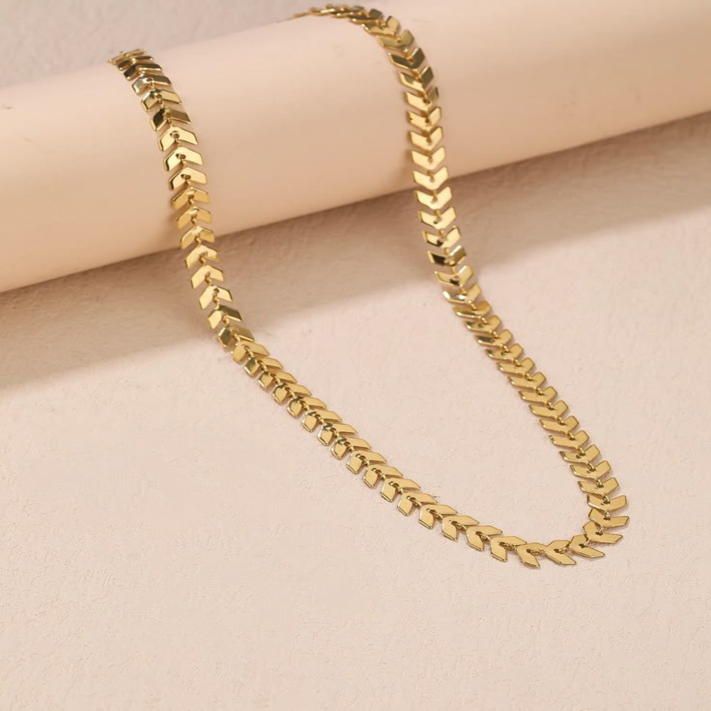 Gold chain necklace on a beige surface