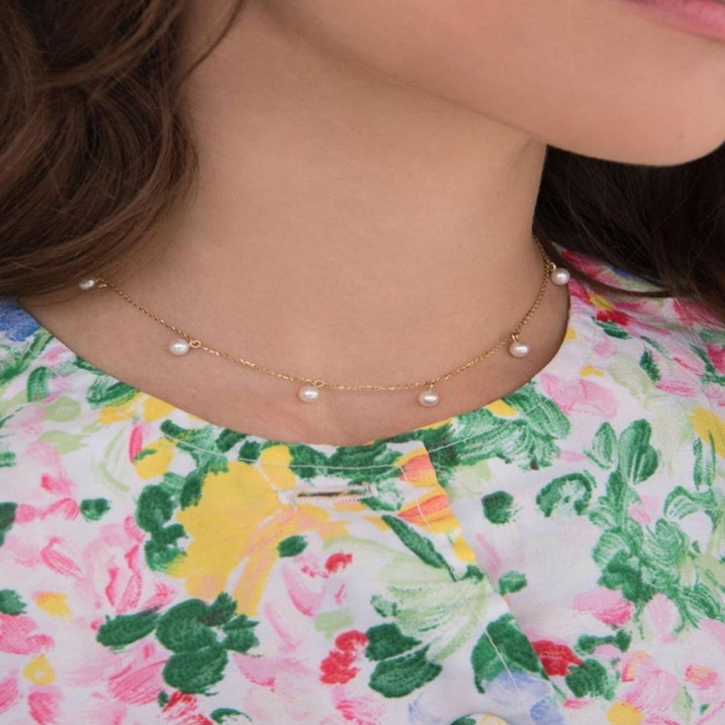 Pearl necklace on a person wearing a floral dress.