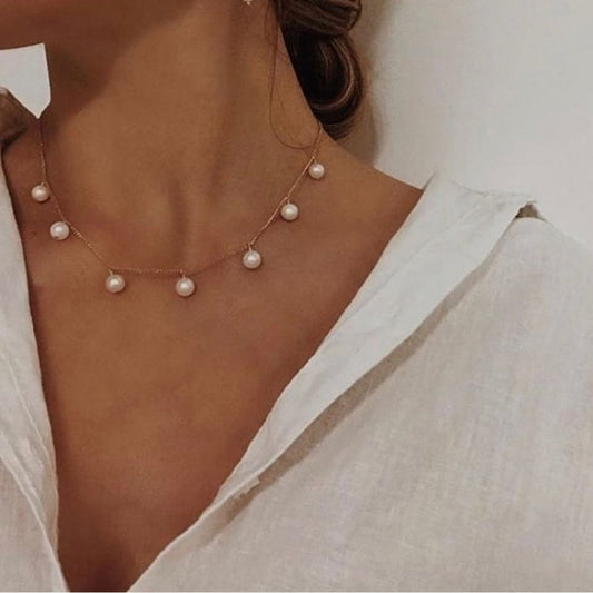 Pearl necklace worn by a person with a white blouse.