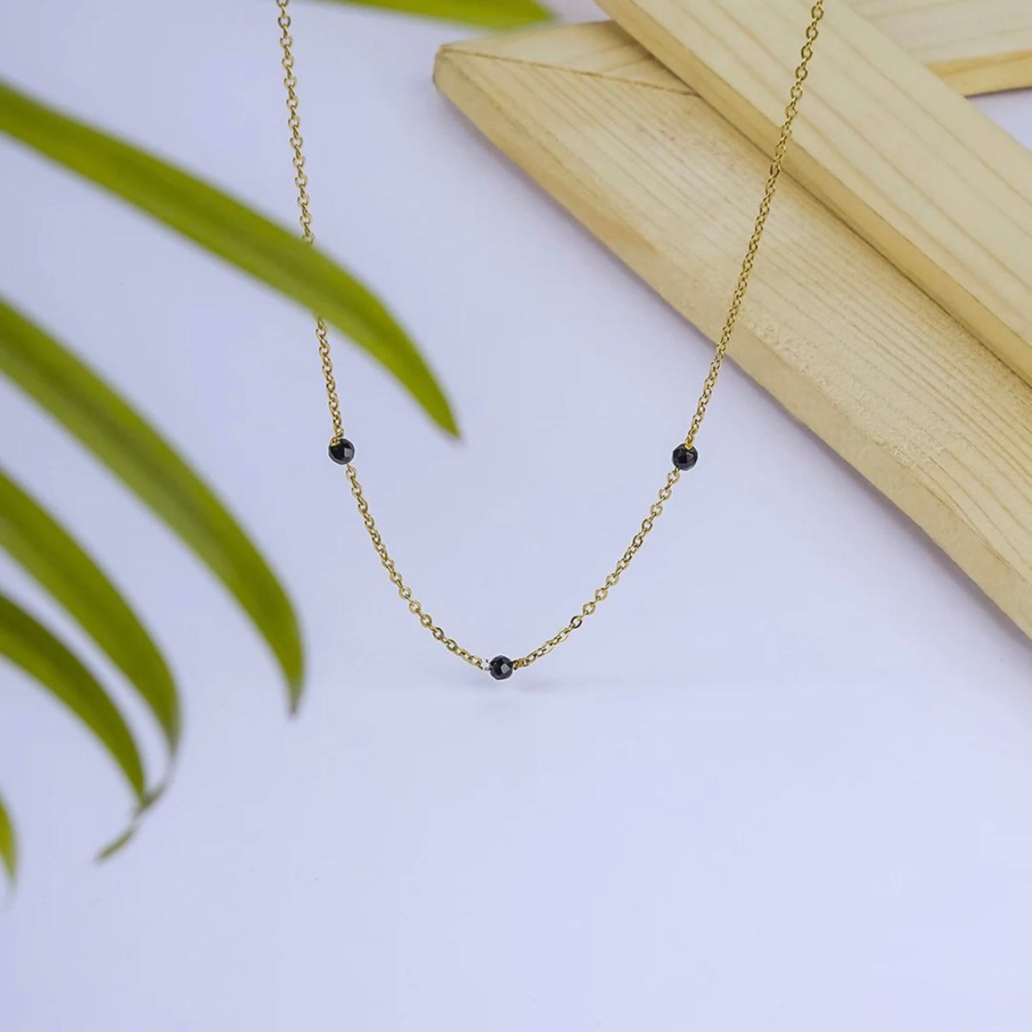 Gold necklace with black beads on a light background