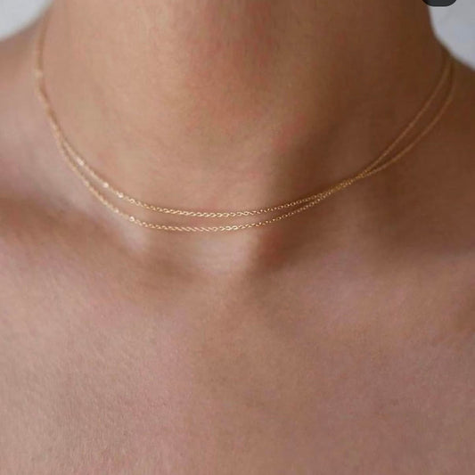 Gold necklace on a person's neck with a neutral background