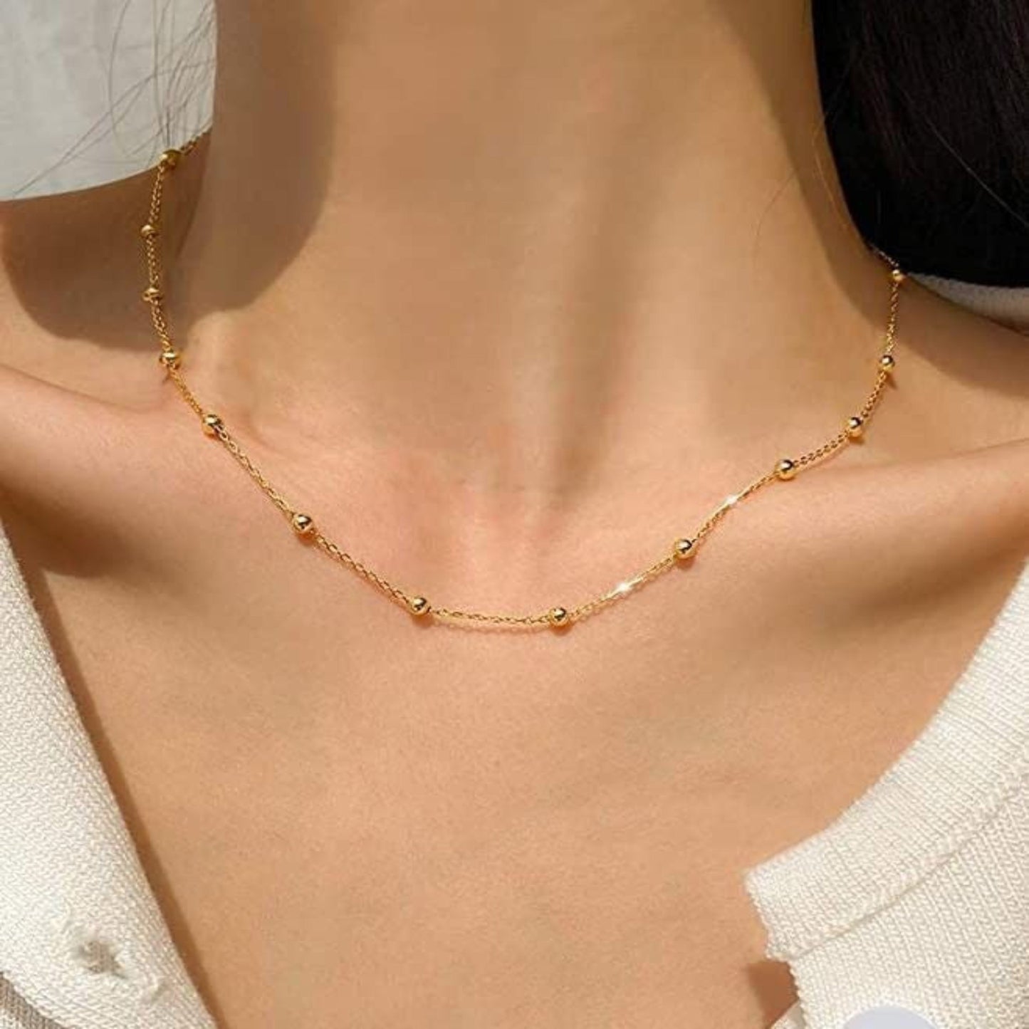 Gold necklace on a person wearing a white top