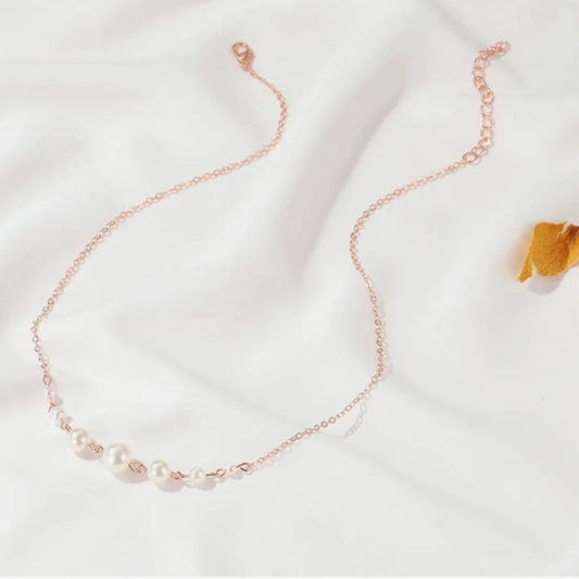 Rose gold necklace with pearls on a white background