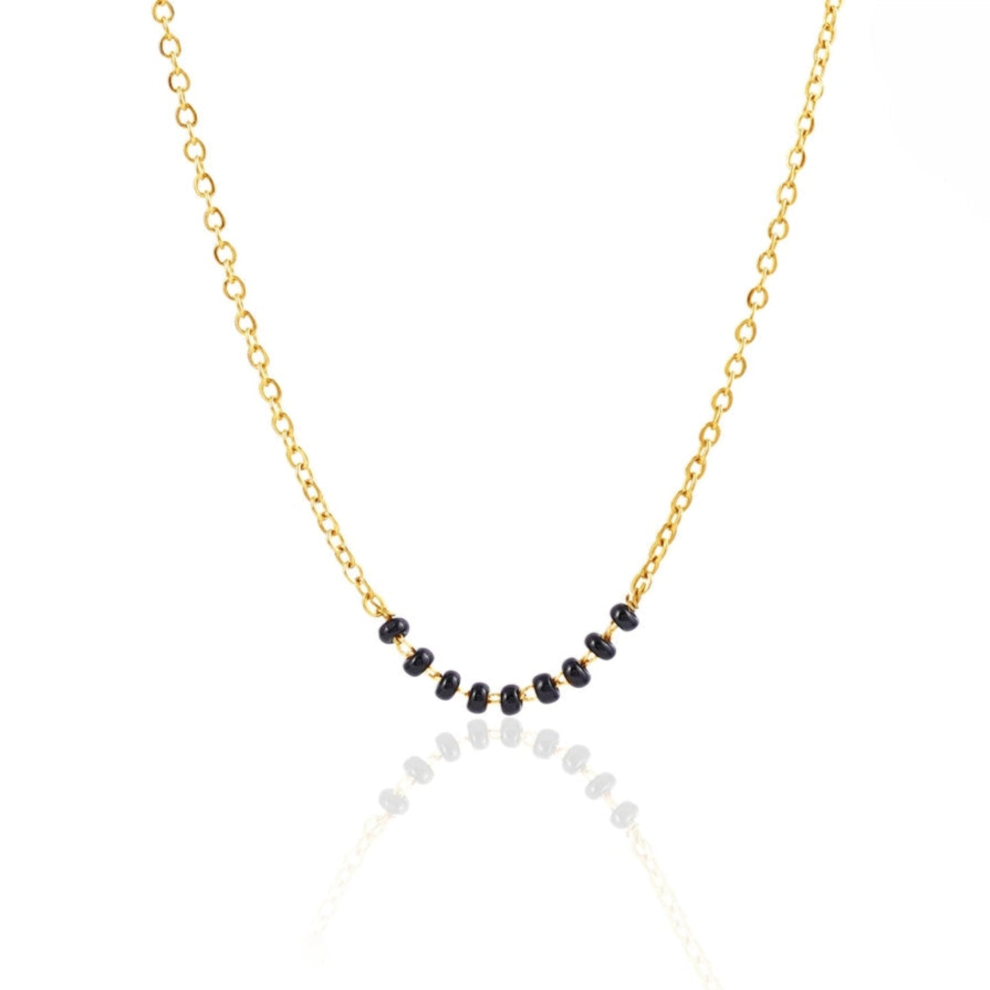 Necklace with black and white beads on a gold chain against a white background