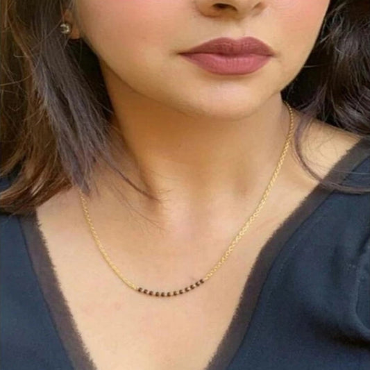 Close-up of a person wearing a gold necklace with a dark blue top.