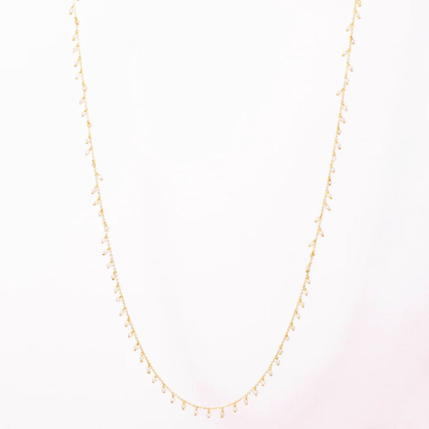 Gold necklace on a light pink background