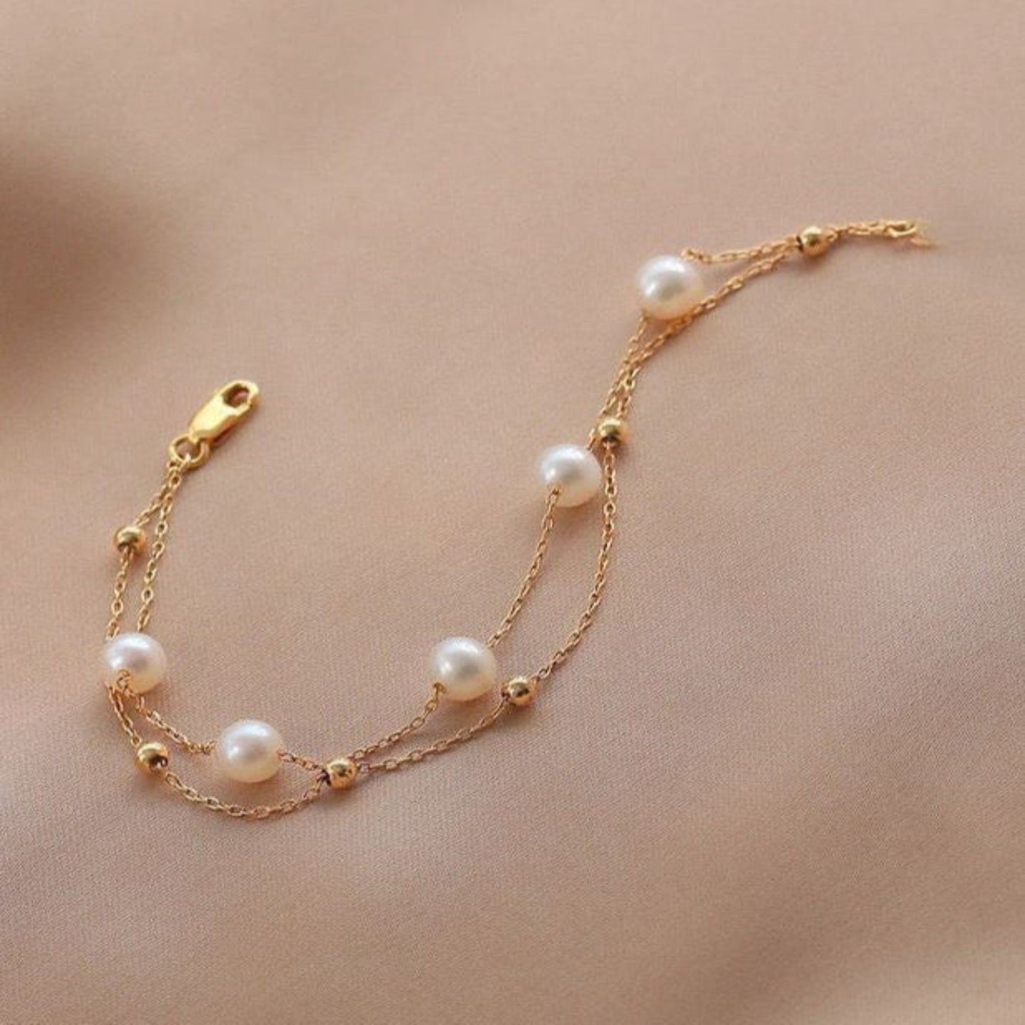Gold bracelet with pearls on a beige background