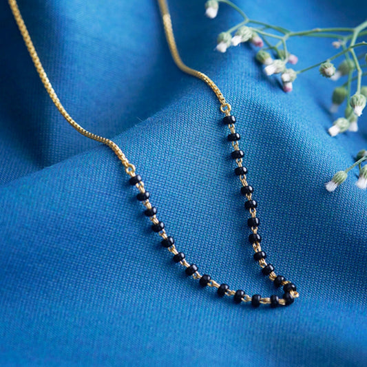 Necklace with black beads on a blue fabric background
