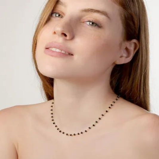Woman wearing a delicate necklace against a plain background