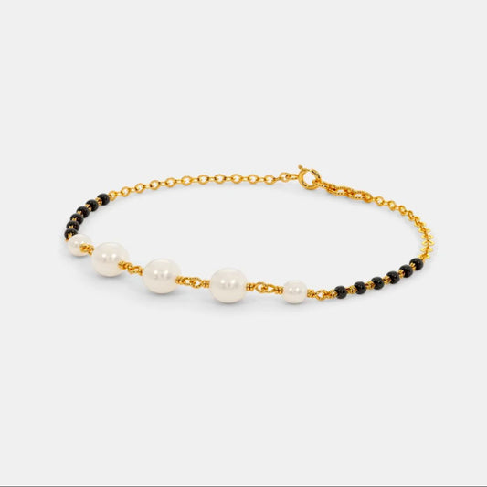 Bracelet with pearls and black beads on a gold chain against a white background
