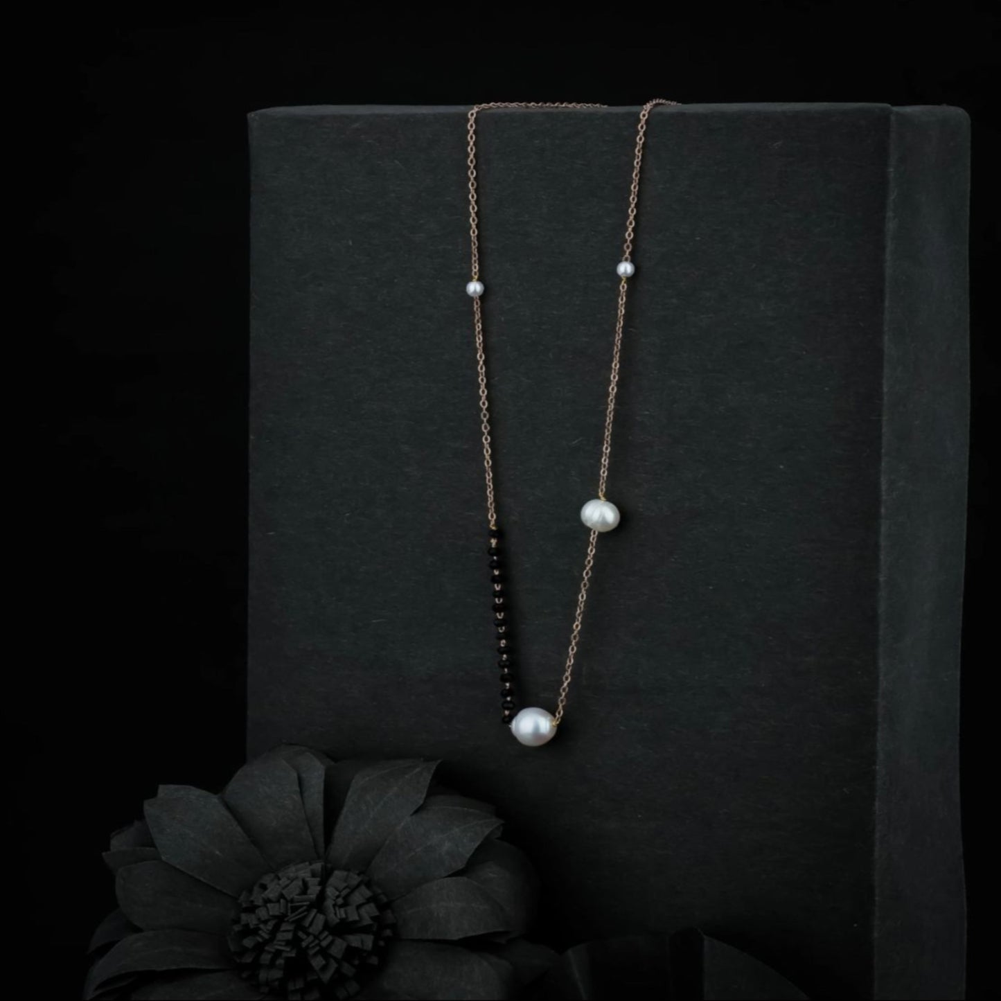 Long necklace with pearls on a black background