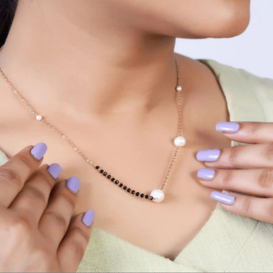 Necklace with pearls and black beads worn by a person with light purple nail polish.