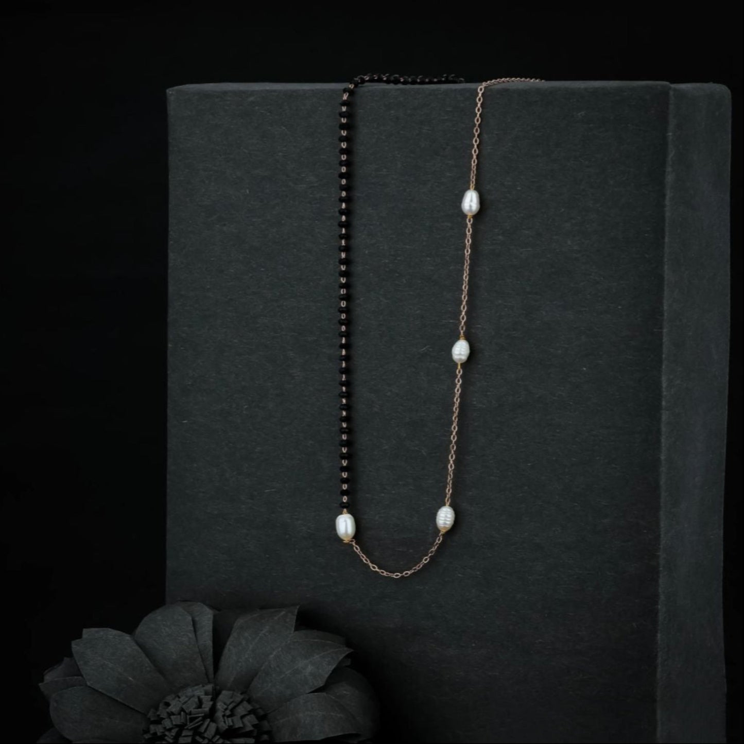 Pearl necklace on a black stand with a dark background