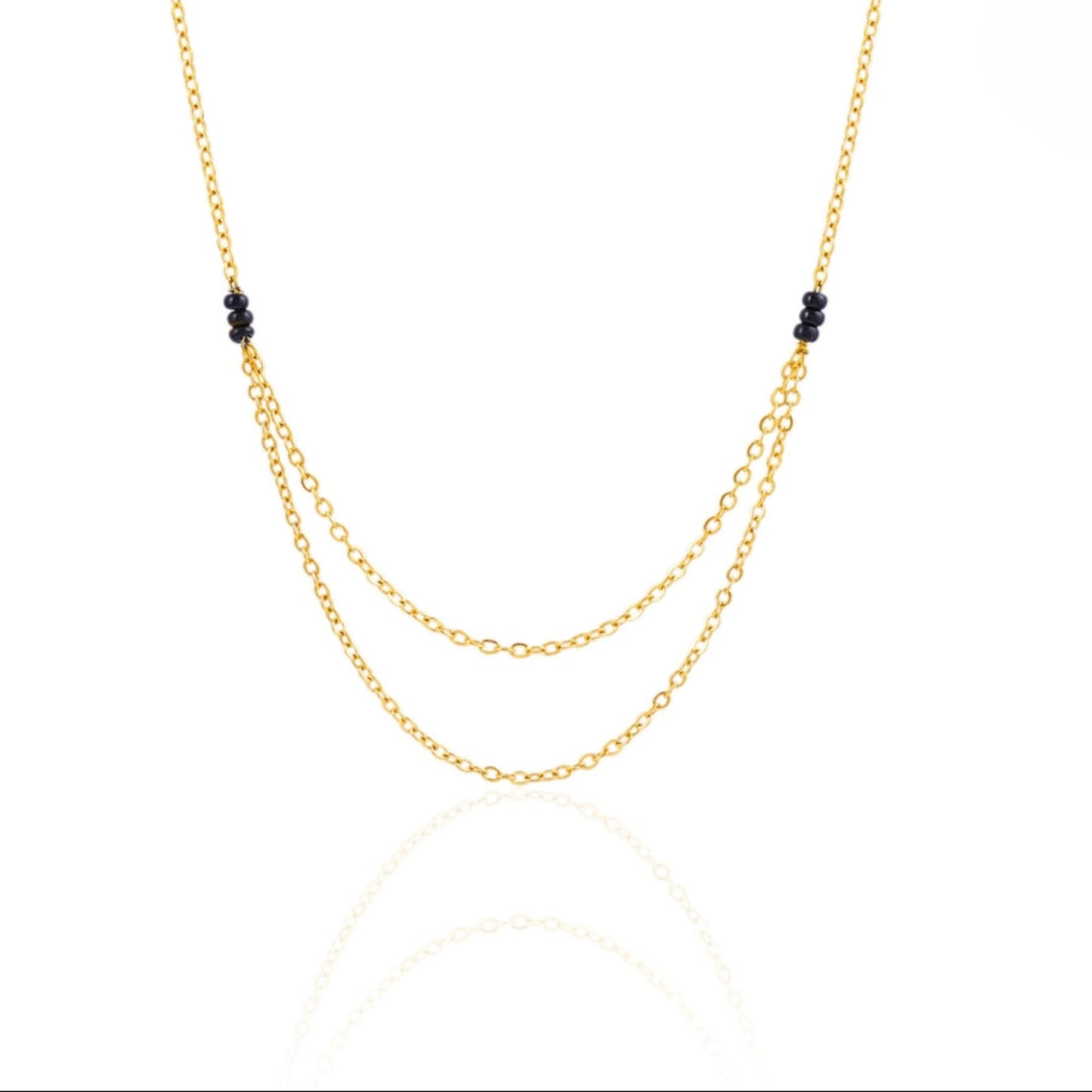 Gold necklace with black beads on a white background