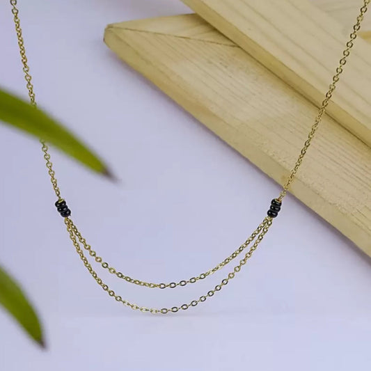 Gold necklace with black beads on a light surface