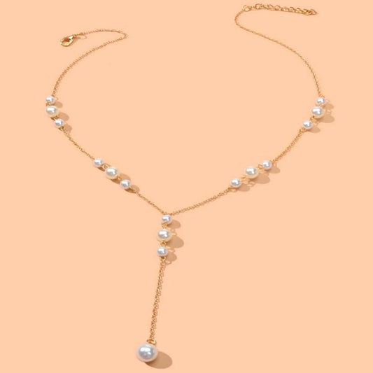 Gold necklace with pearls on a peach background