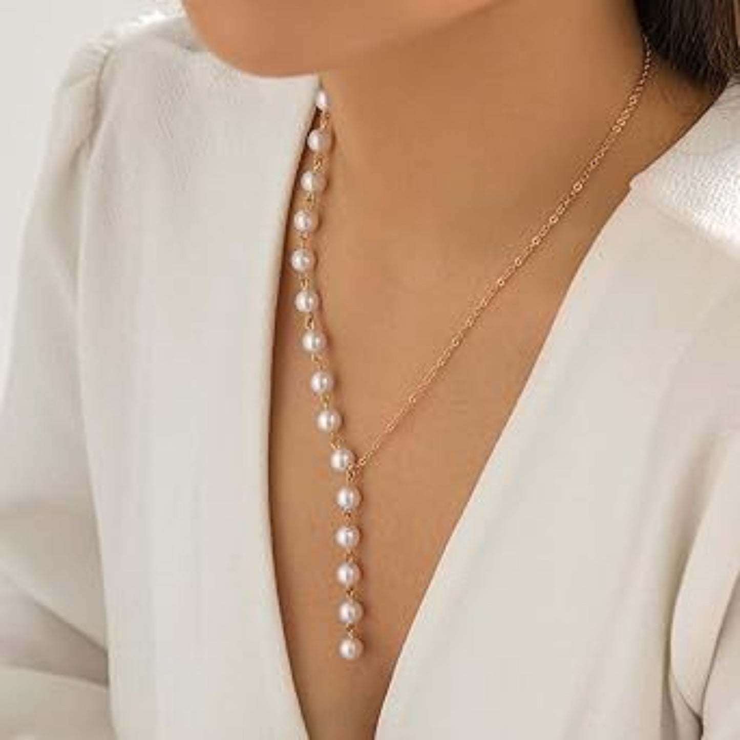 Pearl necklace draped over a white blouse