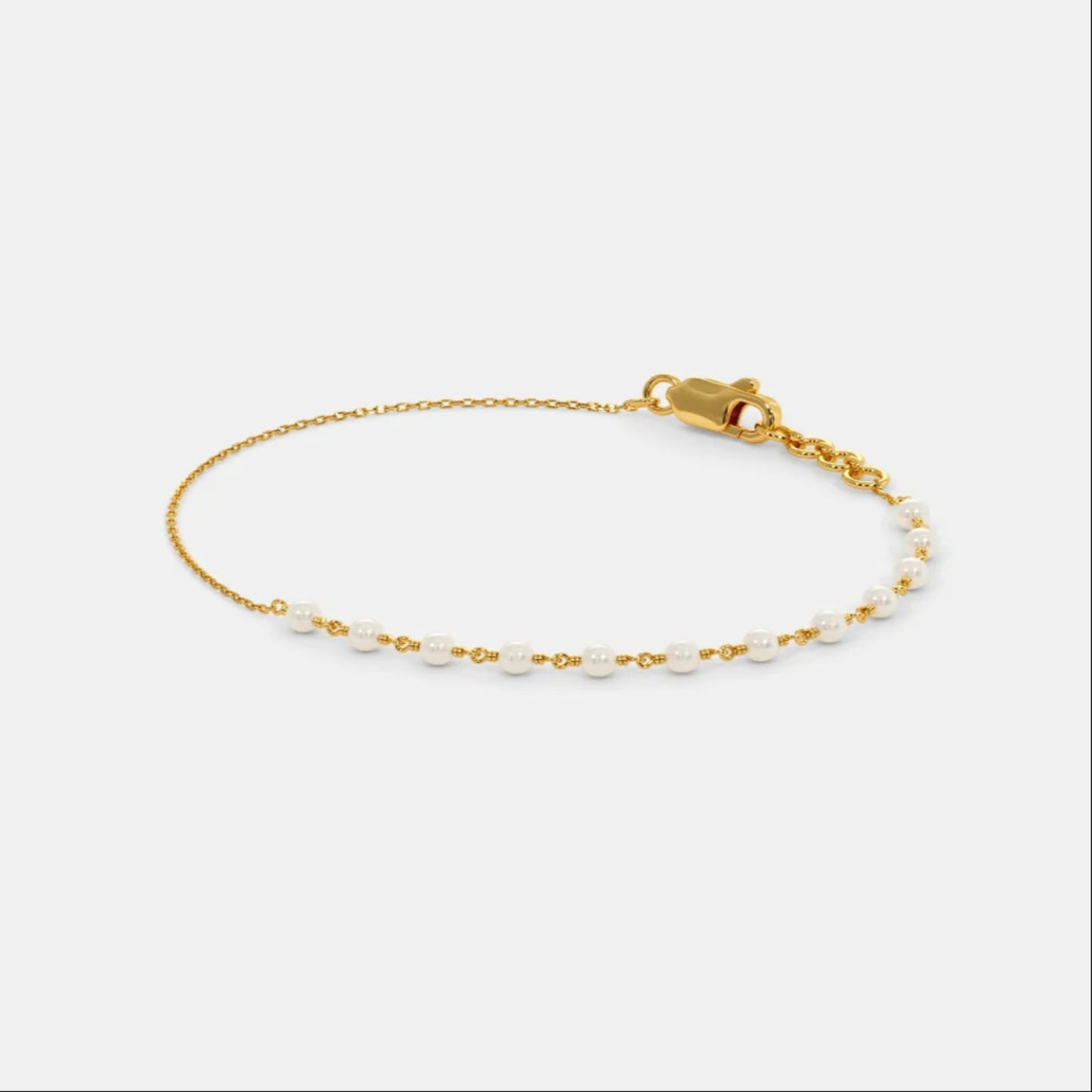 Gold bracelet with small beads on a light gray background