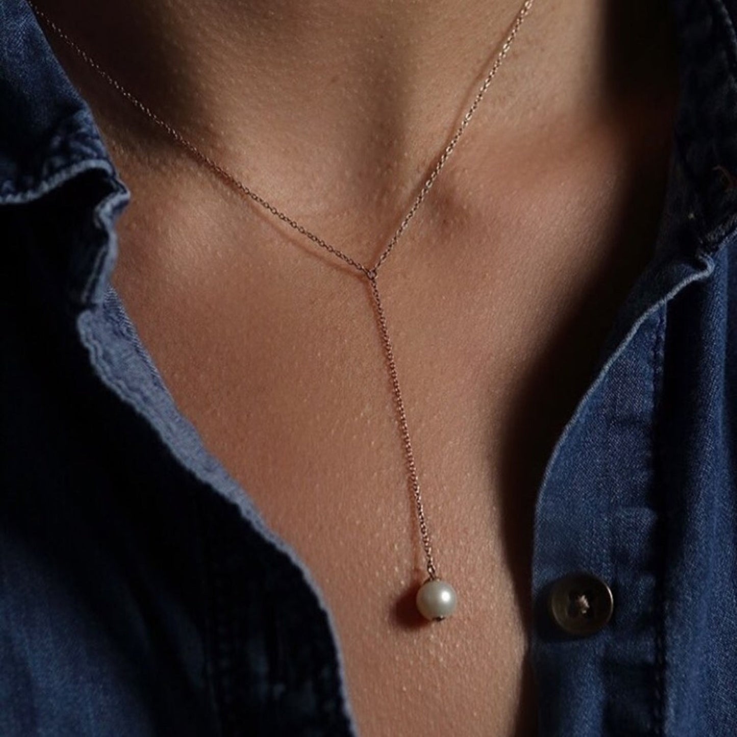 Pearl necklace on a person wearing a blue denim shirt