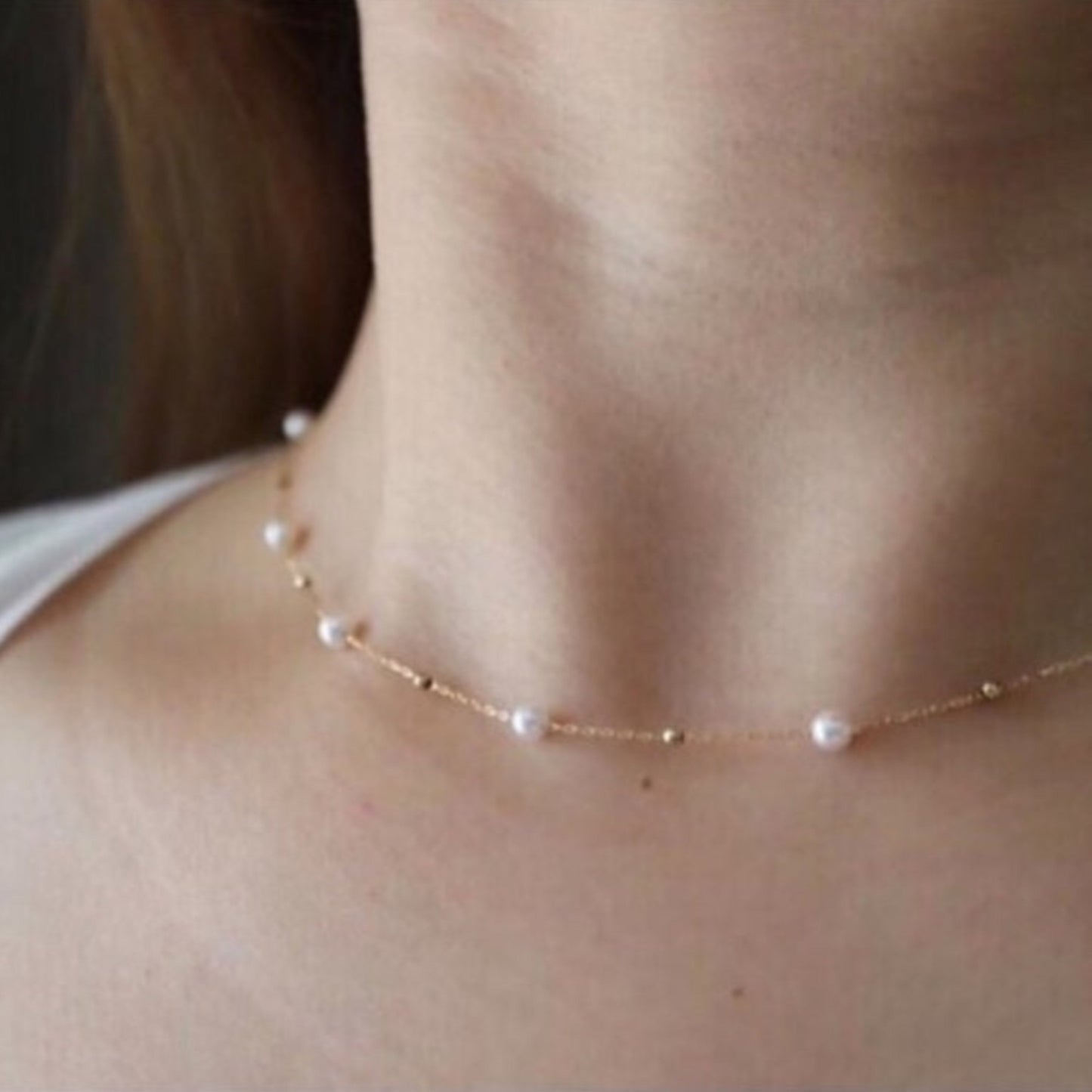 Pearl necklace worn by a person with a neutral background
