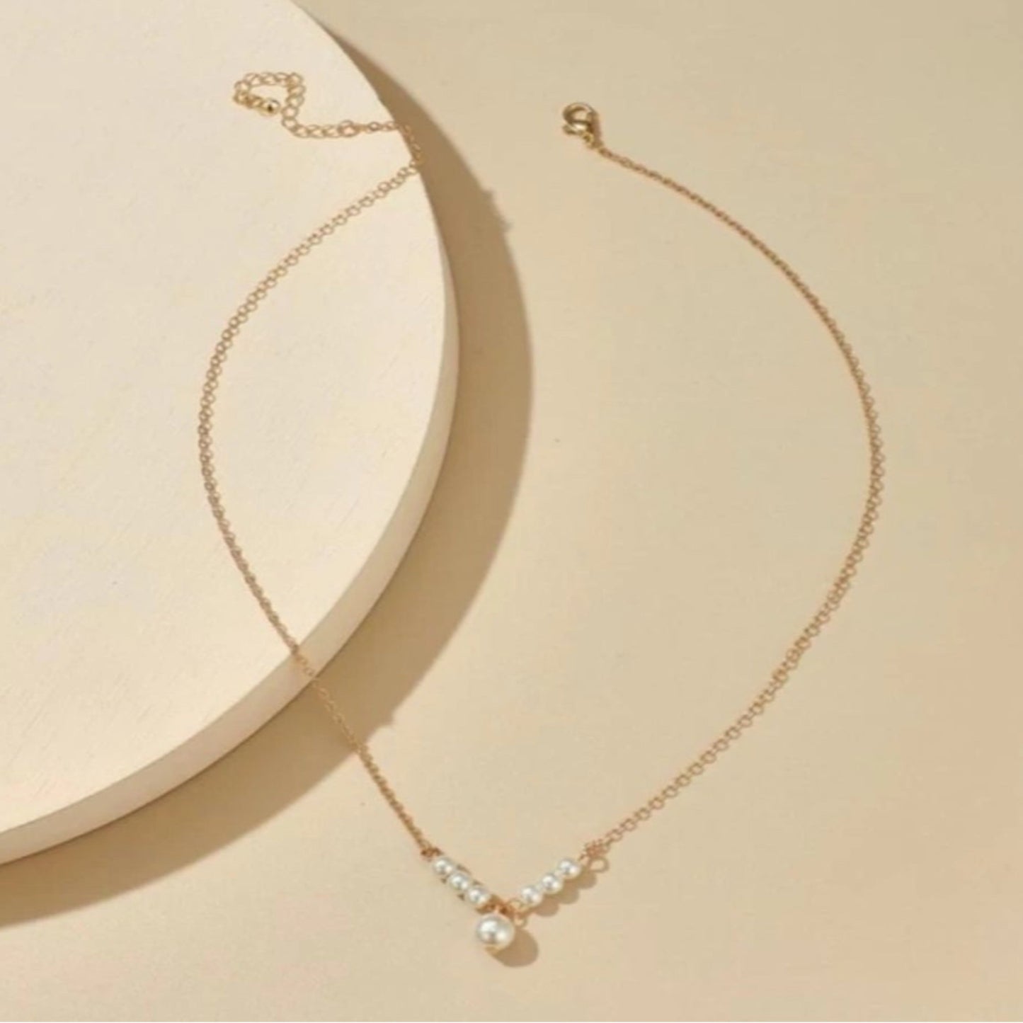Gold necklace with pearls on a beige background