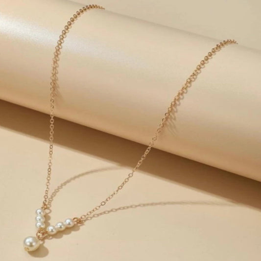 Delicate gold necklace with pearls on a beige background