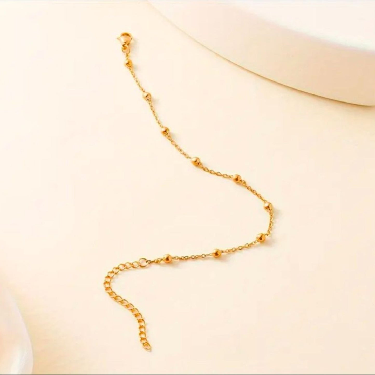 Gold chain bracelet on a light beige background