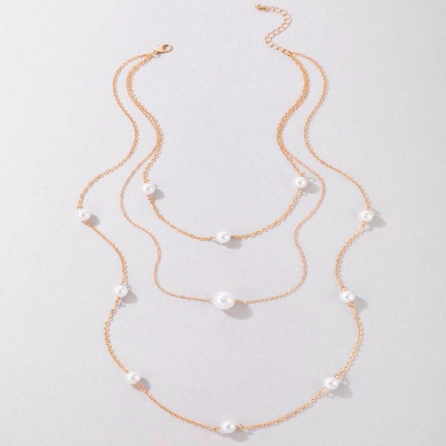 Two layered pearl necklaces on a light gray background