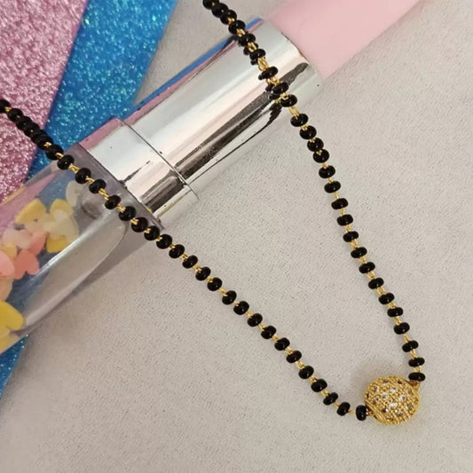 Black beaded necklace with a gold pendant on a gray surface
