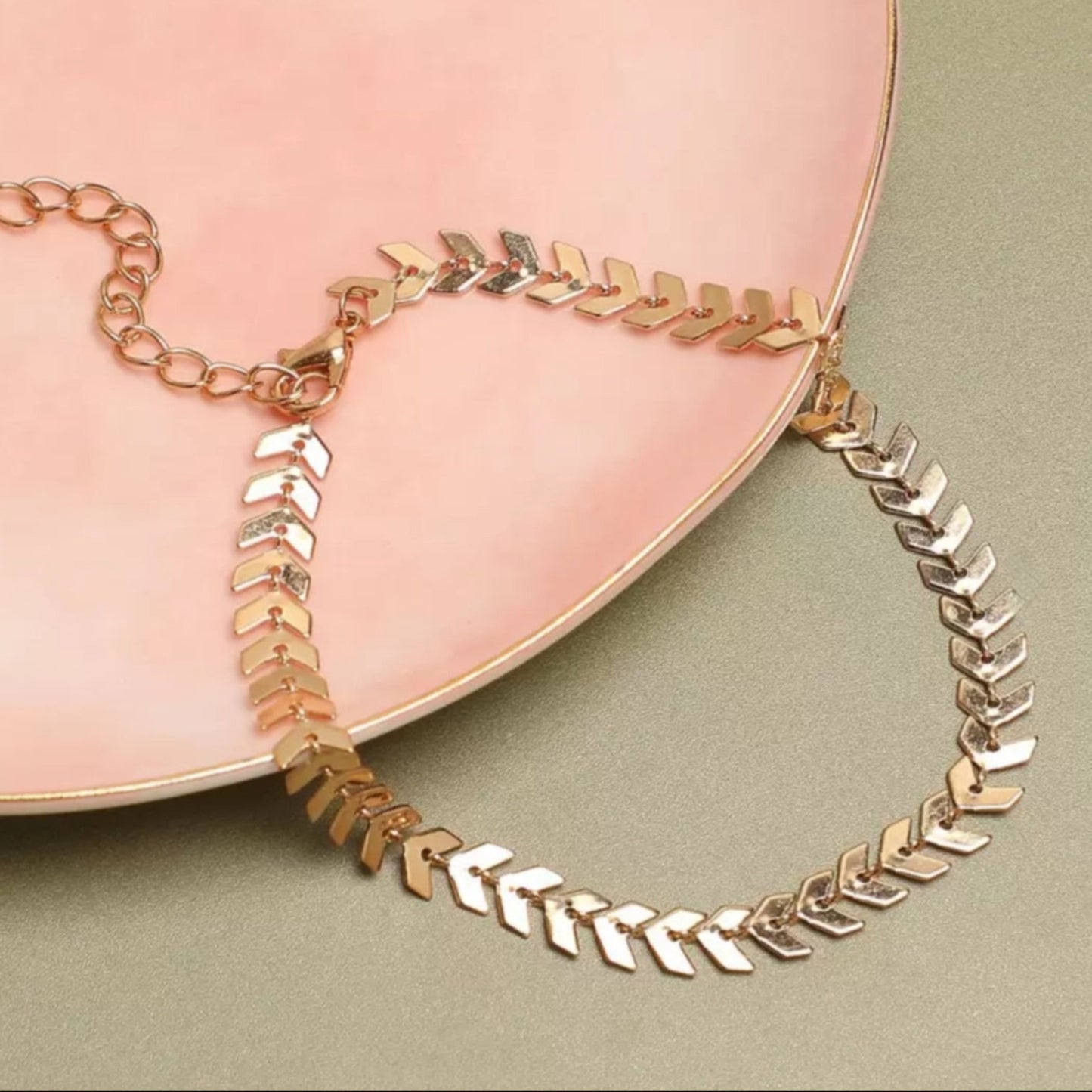 Necklace with leaf-like design on a pink plate