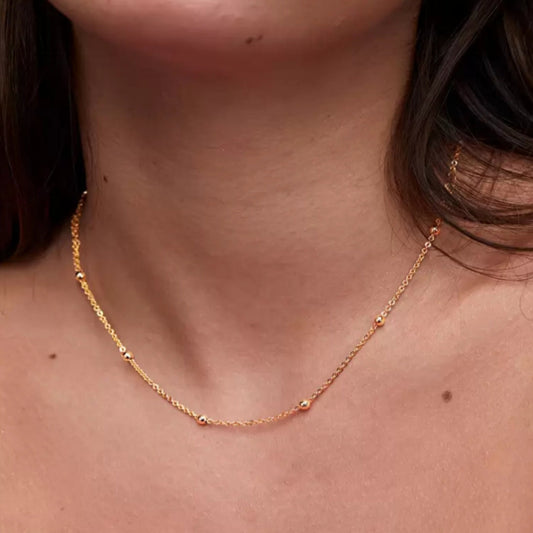 Gold necklace on a person wearing a pink top