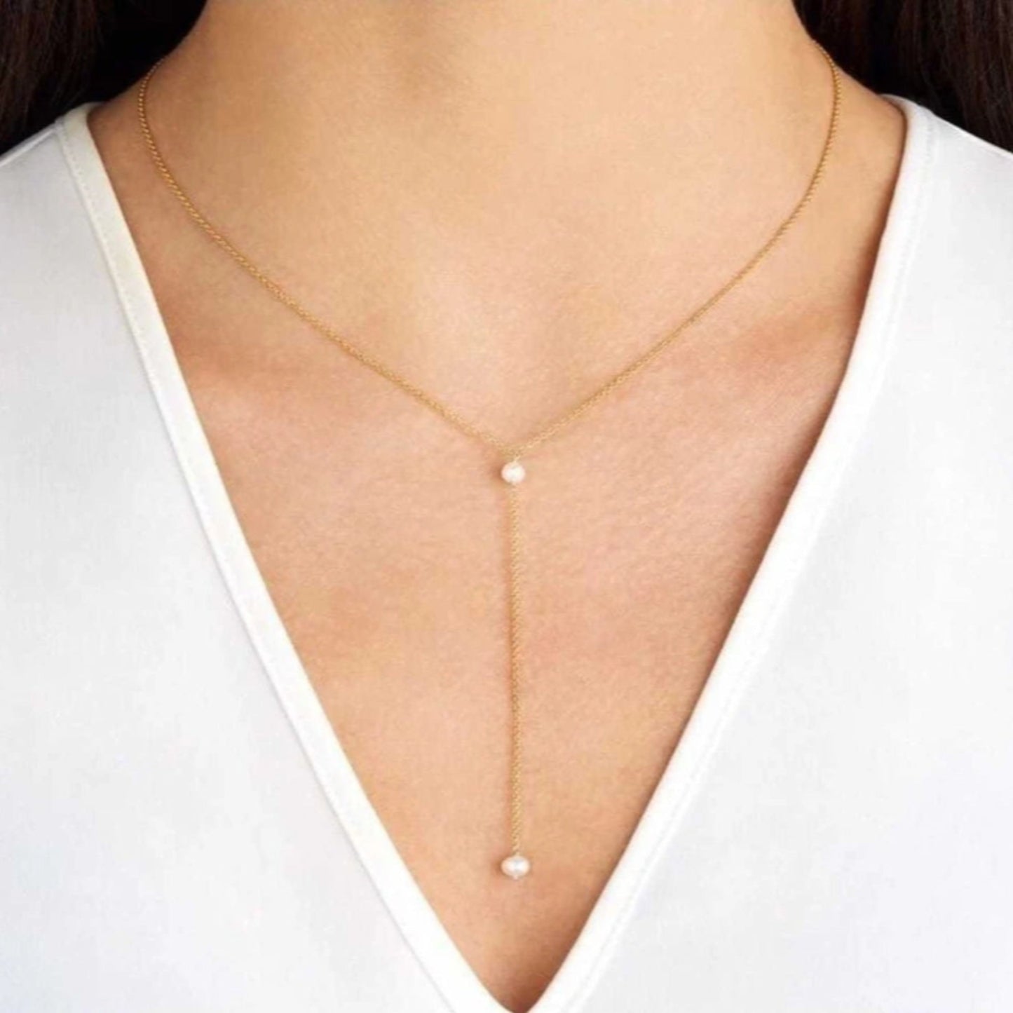 Gold necklace with a pearl pendant on a white background