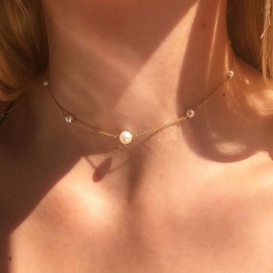 Close-up of a pearl necklace on a person's neck with a blurred background