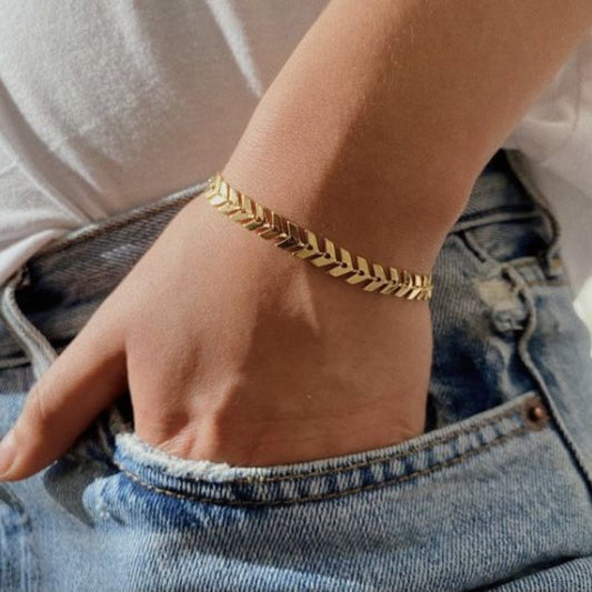 Gold bracelet on a wrist with a neutral background