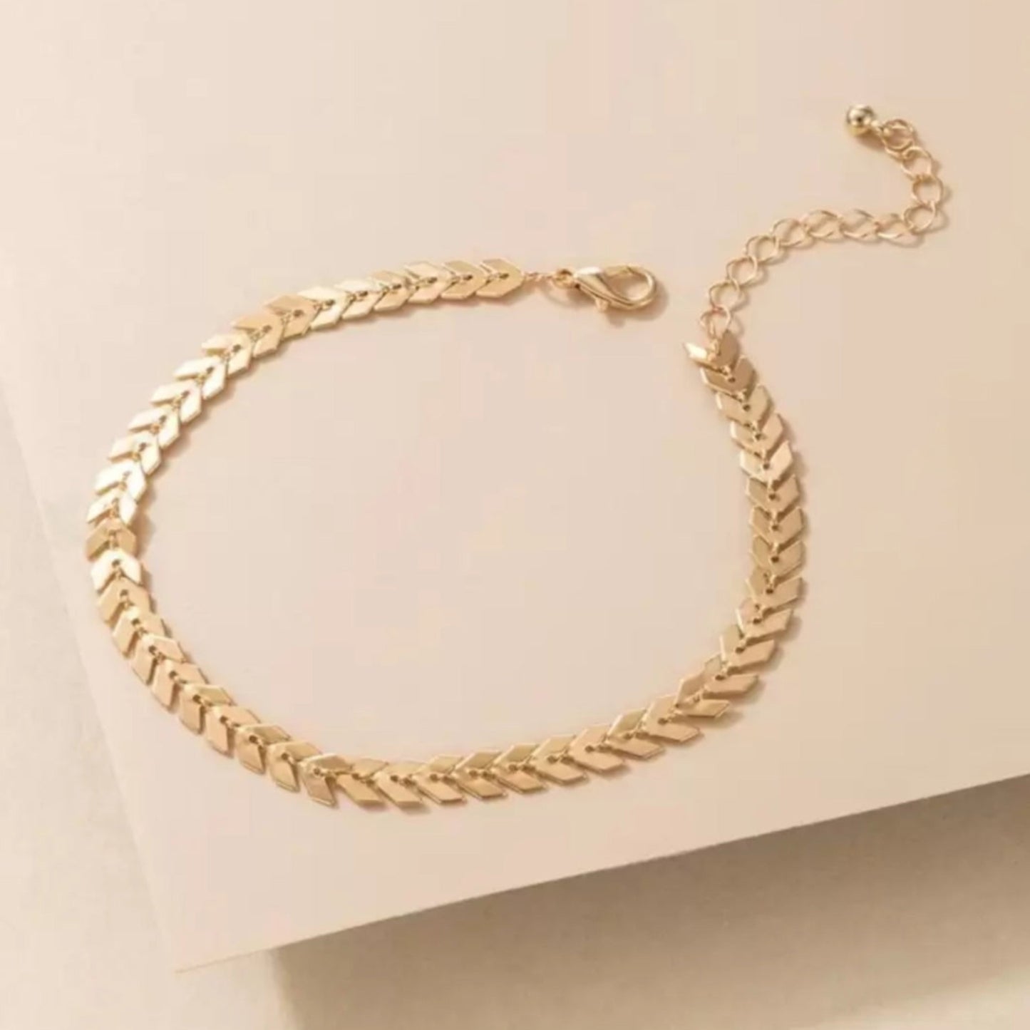 Gold chain bracelet on a beige background