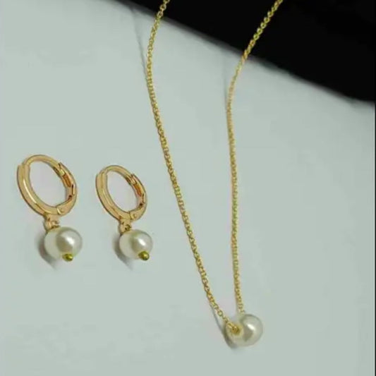 Gold necklace with pearl pendants and matching earrings on a light gray background