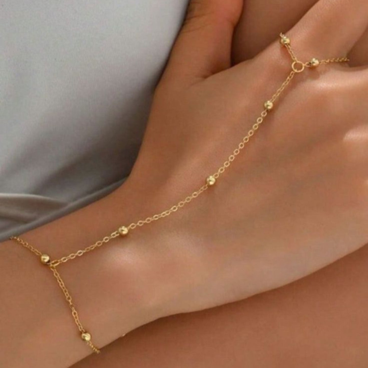 Gold anklet on a person's ankle with a neutral background