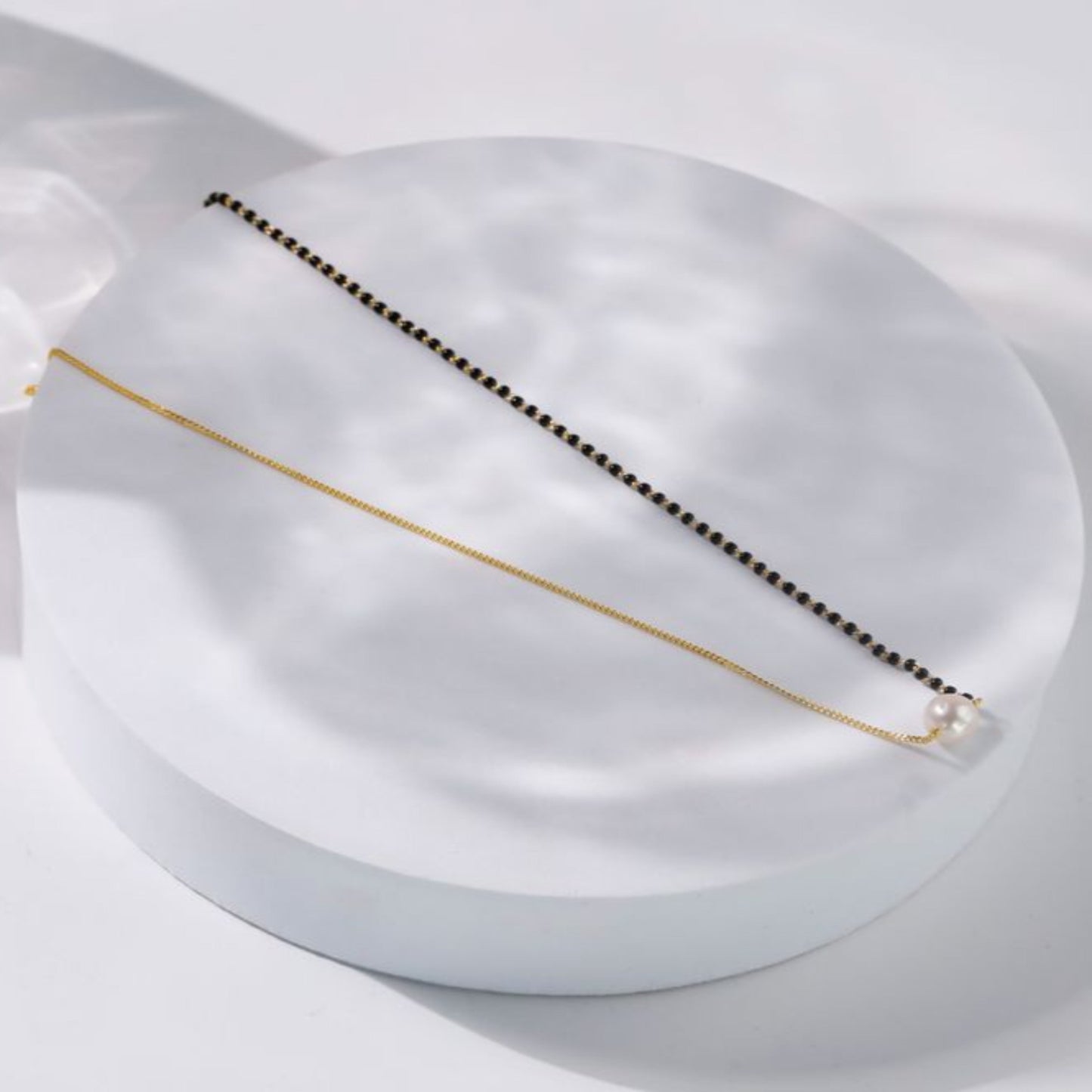 Gold and black beaded necklace on a white surface