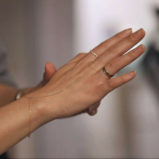 Hand with gold bracelet and ring on a blurred background