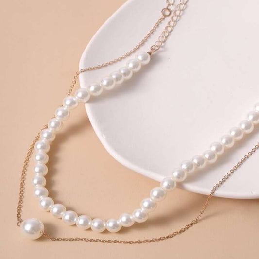 Pearl necklace on a beige background with a white plate