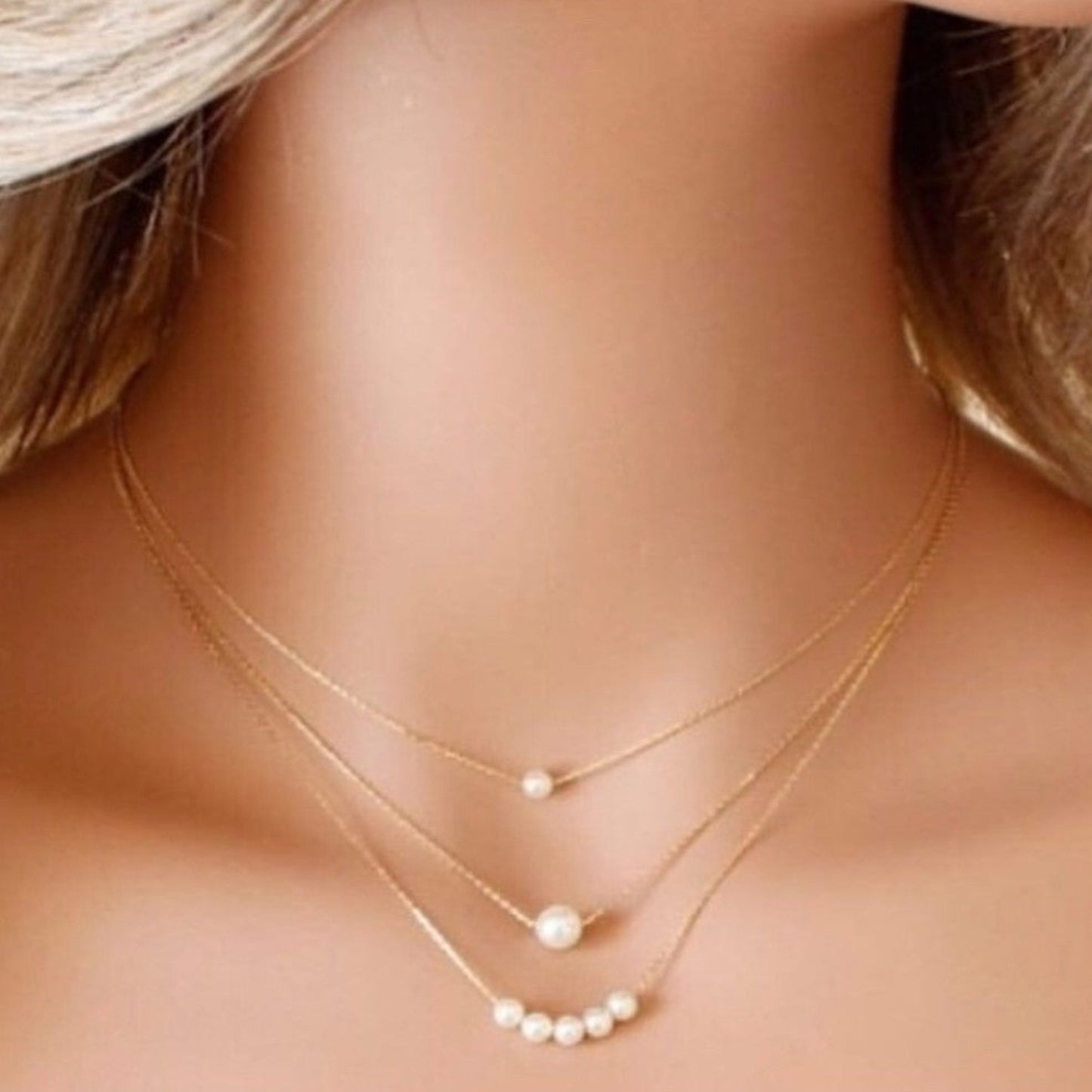 Gold necklaces with pearl pendants on a mannequin