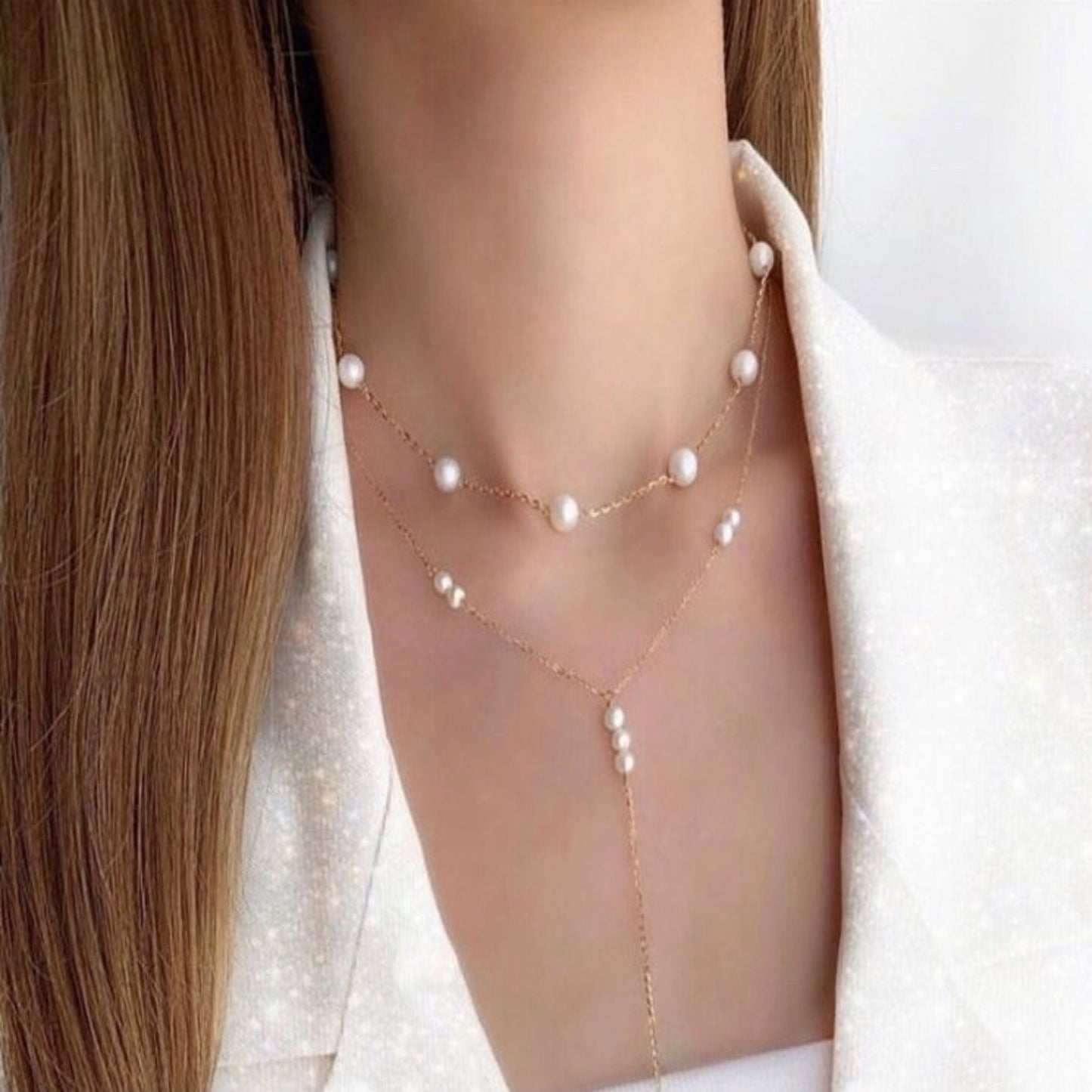 Pearl necklace worn by a person with a neutral background