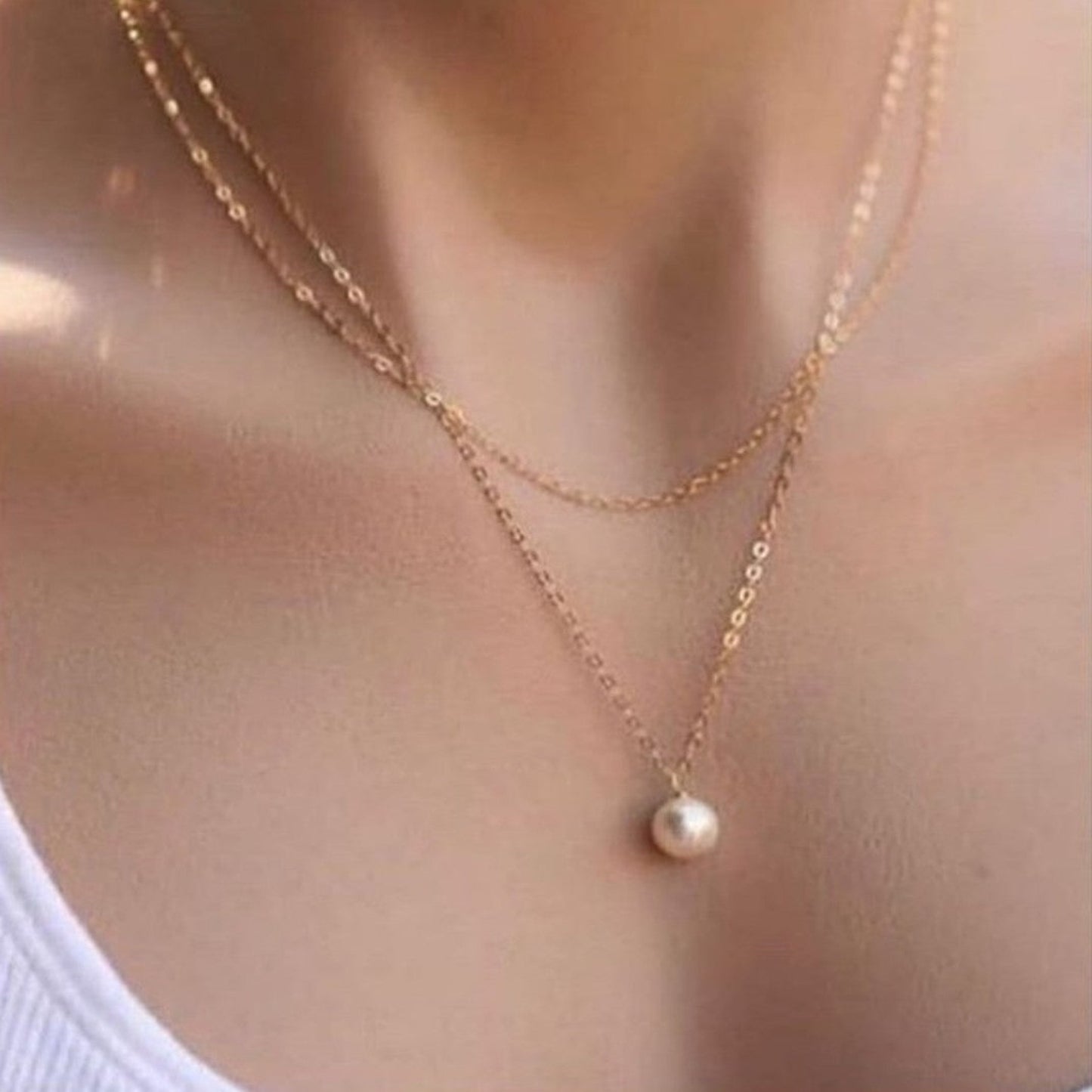 Gold necklace with a pearl pendant on a blurred background