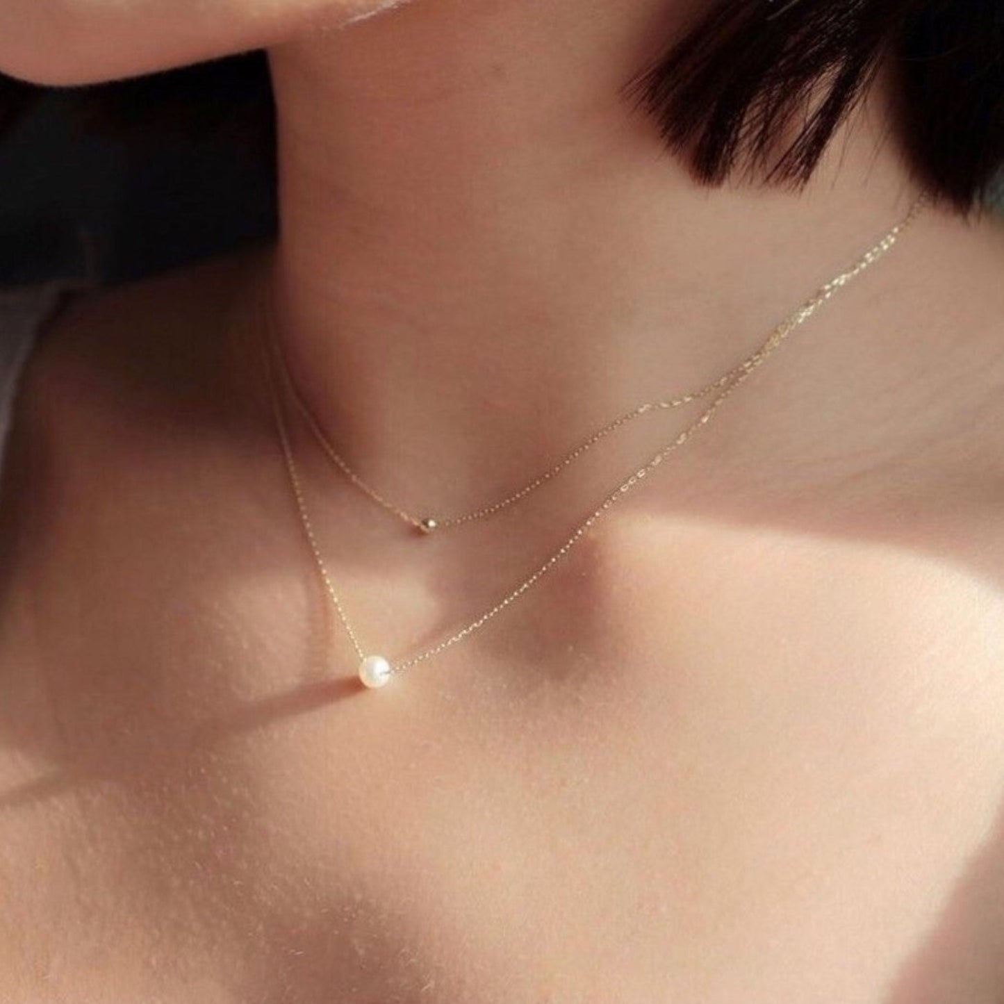 Gold necklace with a pearl pendant on a person's neck