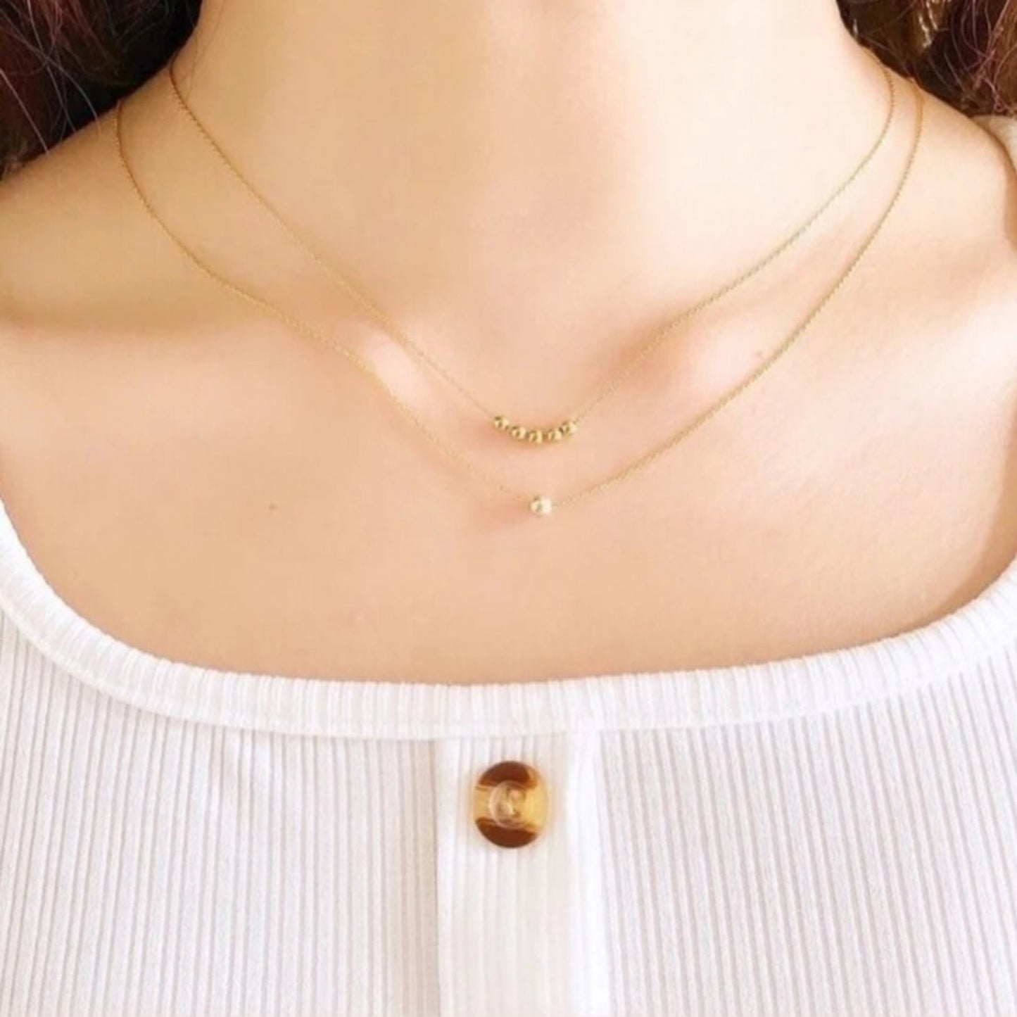 Gold necklace on a mannequin with a white top