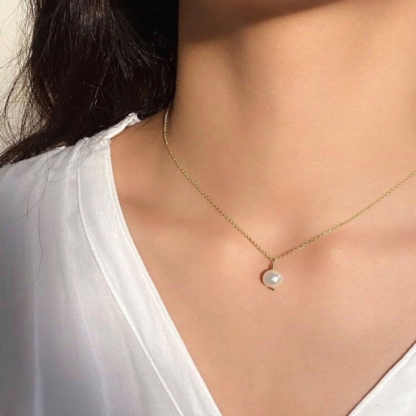 Pearl necklace on a person wearing a white top