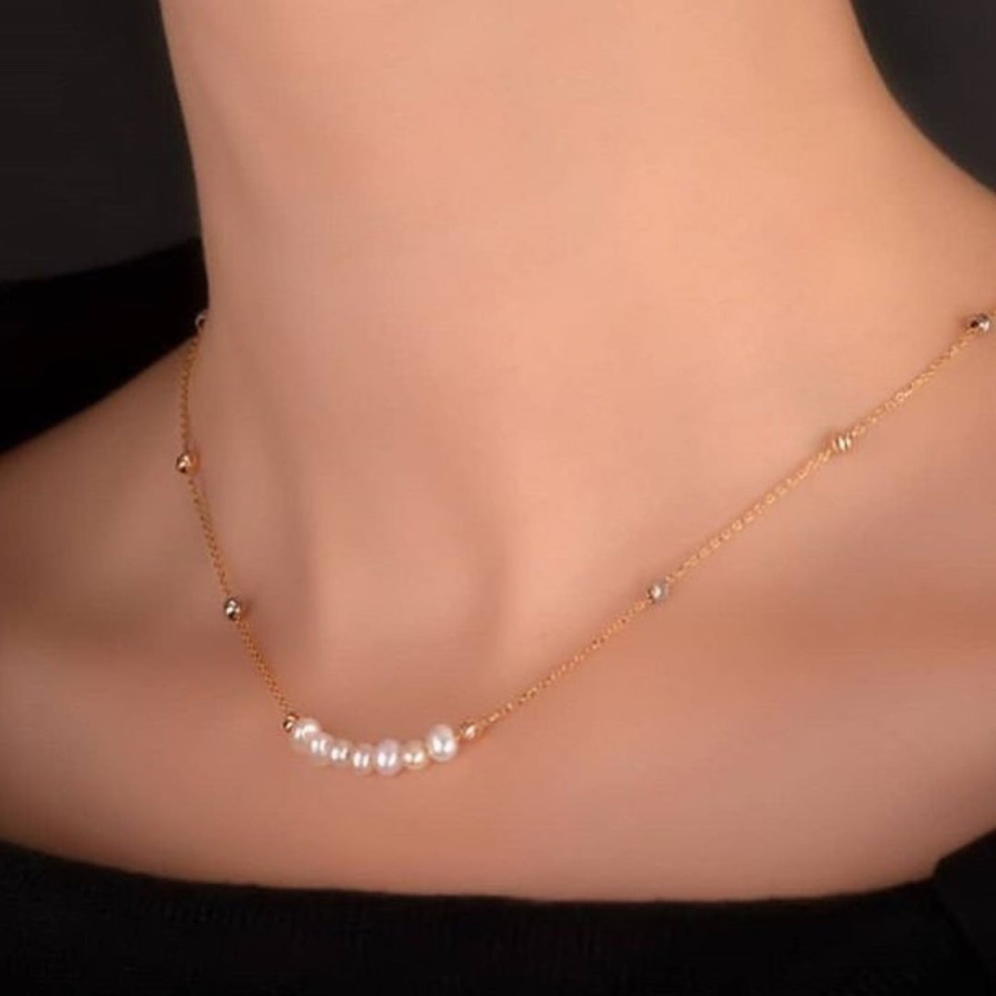 Gold anklet with pearls on a person's ankle against a dark background