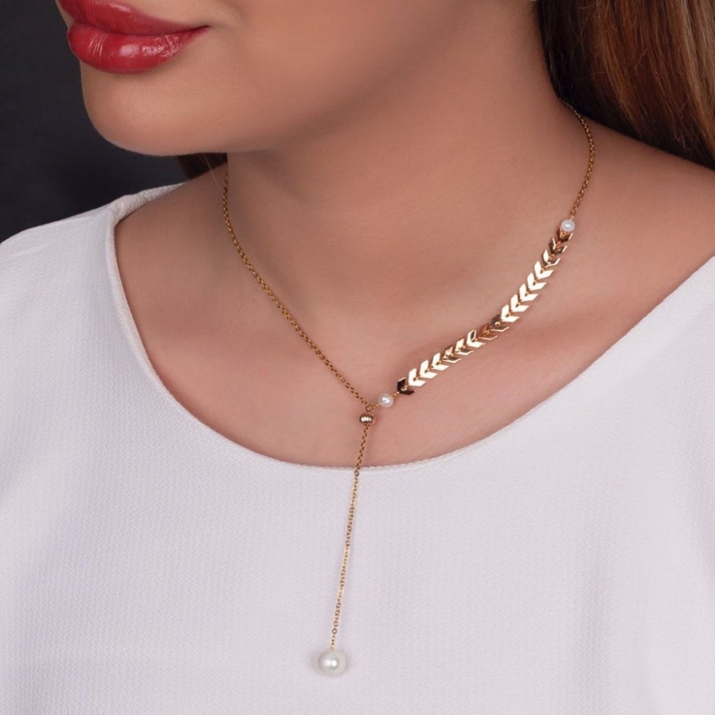 Gold necklace with pearl pendant on a model wearing a white top